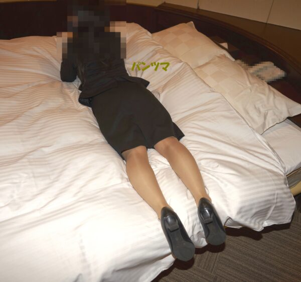 リクルートスーツを着た女性がベッドで横たわる